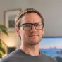 Mike Stott — head-and-shoulders portrait in a gray sweater and dark-framed glasses